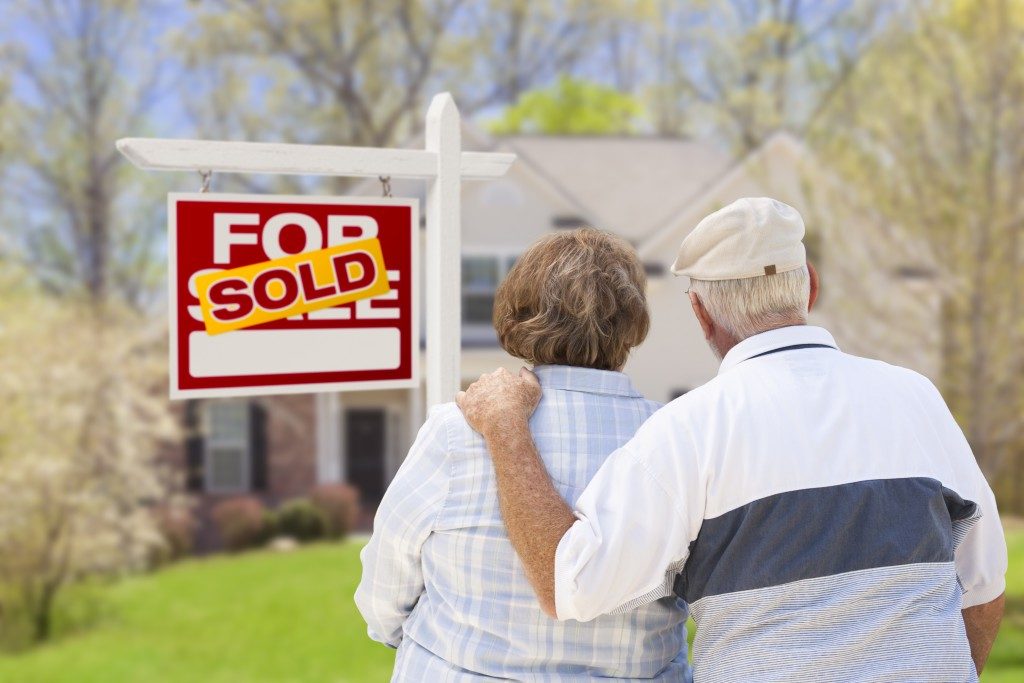 couple in front of sold real estate sign