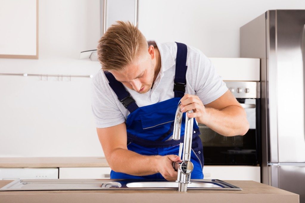 Plumber fixing the faucet in a house