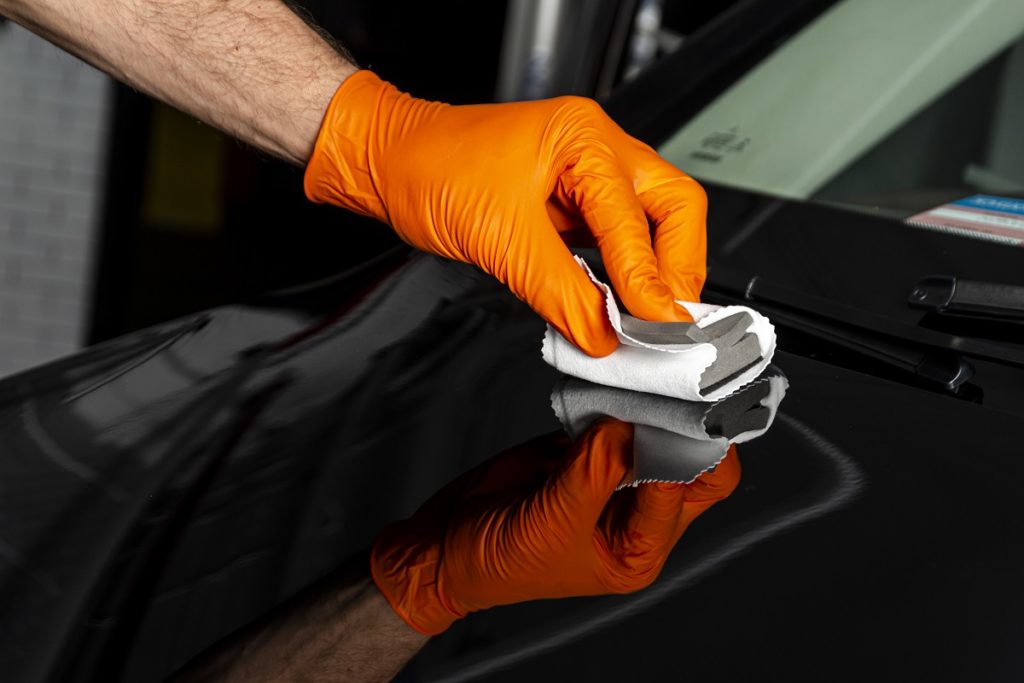 Car polish wax worker hands polishing car.