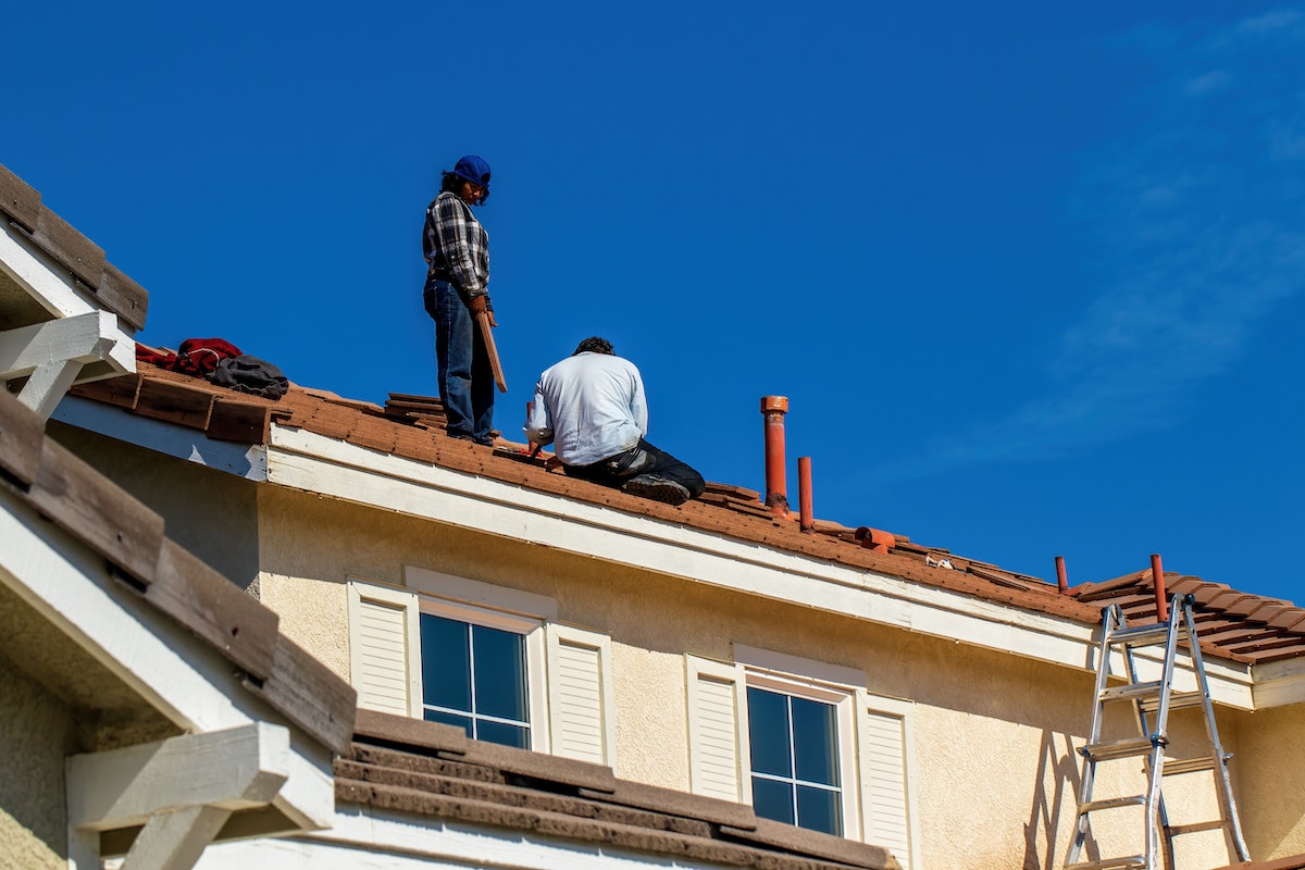 Low Angle Shot of Builders Fixing a Tiled Roof against Blue Sky